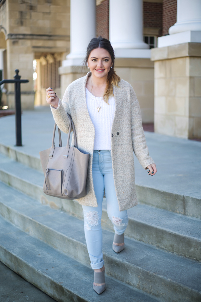 khaki coat, white knit sweater, gold shark tooth necklace, light wash destroyed denim jeans, pointed toe grey mules, grey trapeze bag, gold jewelry