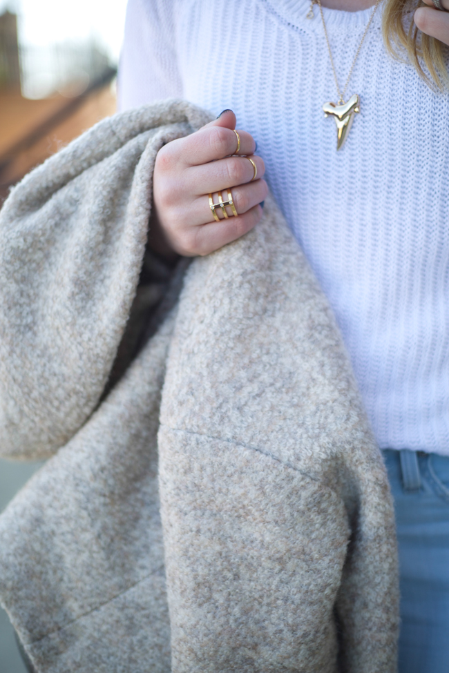 khaki coat, white knit sweater, gold shark tooth necklace, light wash destroyed denim jeans, pointed toe grey mules, grey trapeze bag, gold jewelry